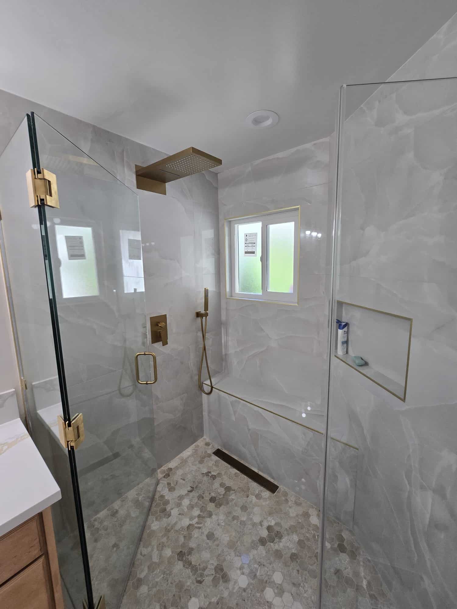 Frameless glass shower with large-format porcelain and brushed gold fixtures in Northridge