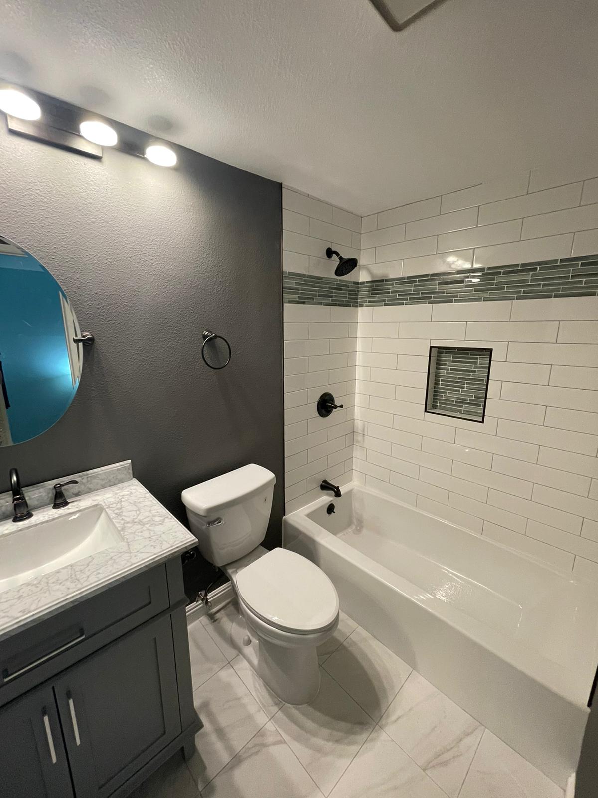 Subway tile tub surround with dark mosaic band in Reseda