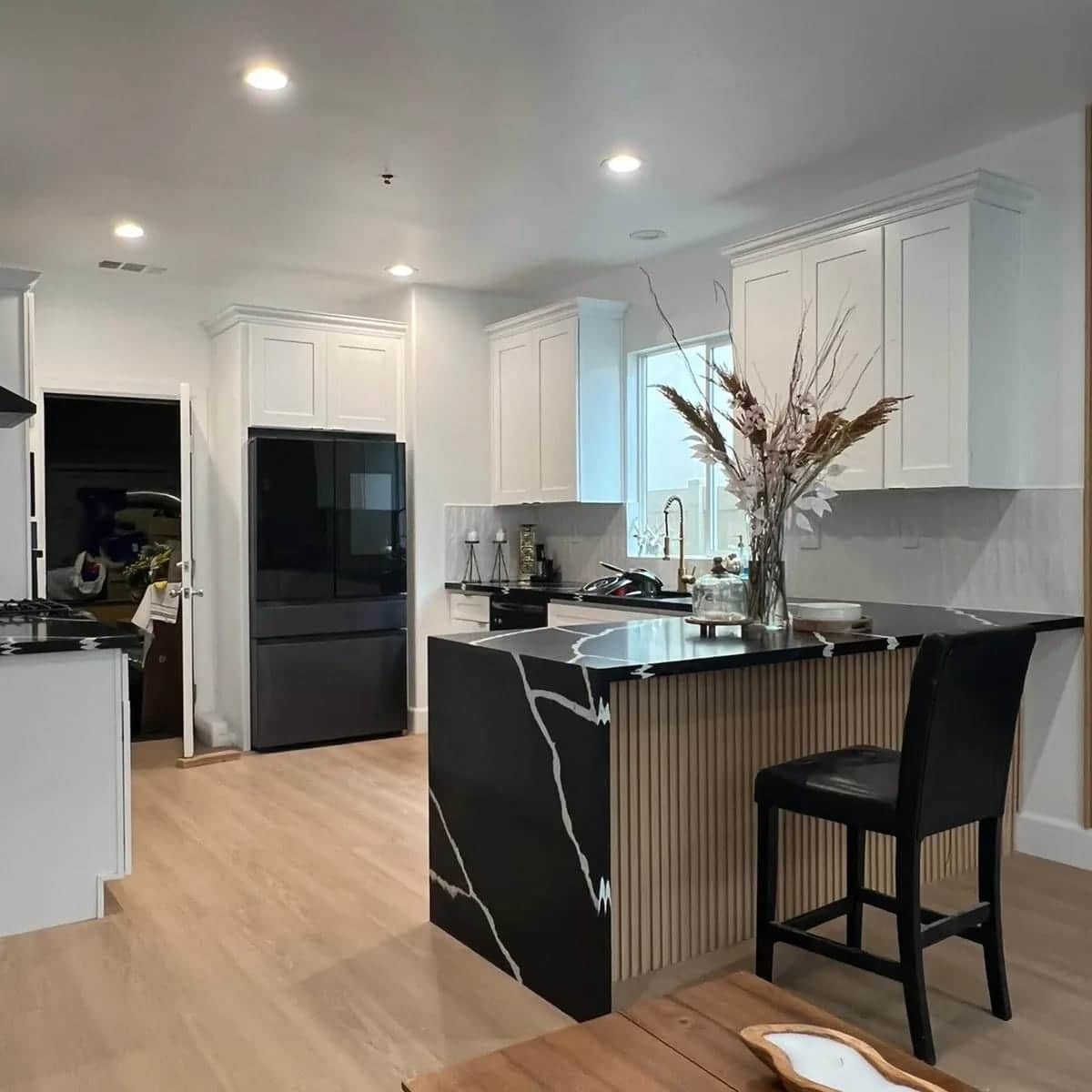 Open-concept kitchen with black quartz waterfall island in Tarzana